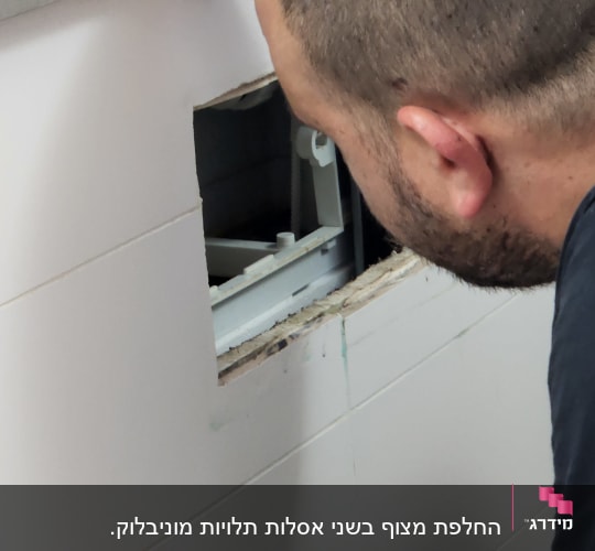 אדם בודק צנרת מאחורי קיר פתוח